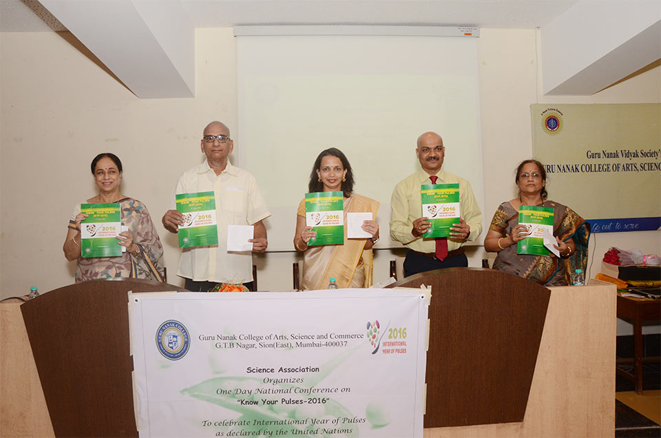 The five presenters at the One Day National Conference on 'Know Your Pulses-2016' lined up behind the podium at the event, each holding an Internation Year of Pulses 2016 brochure